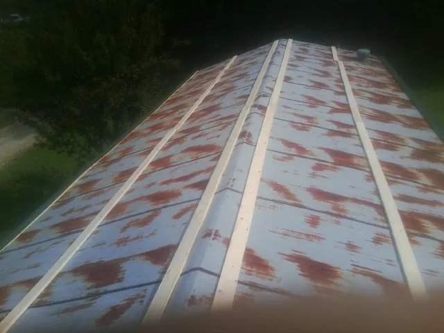 Rusted metal roof panels with new wood purlins before replacement — Storm Damage Roof Repair in Corinne by Roofing Brothers
