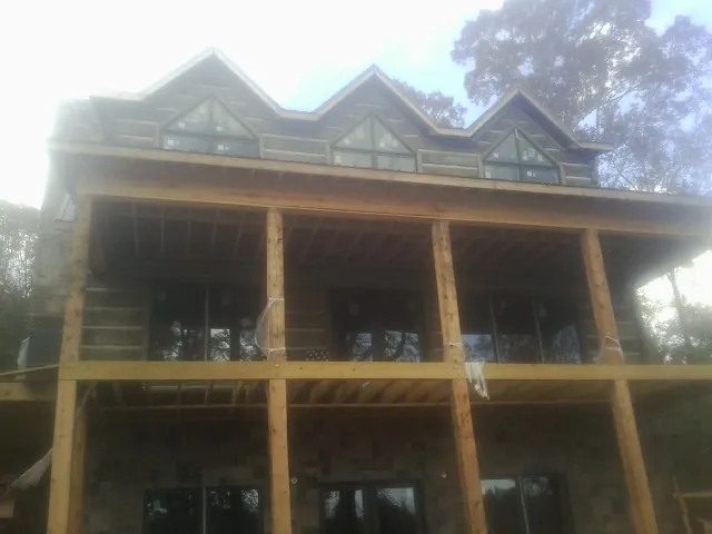 Dormers and porch framing on a large log home under construction — Roof Coating work by our crew in Corinne