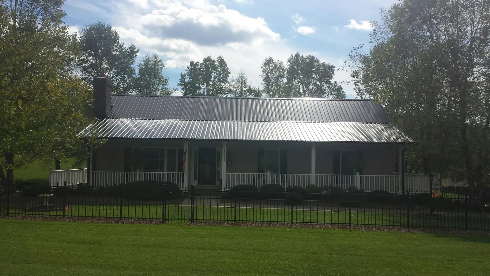 Gray metal roof on a brick ranch with a full width front porch — Gutter Guard Installation work by our crew in Corinne
