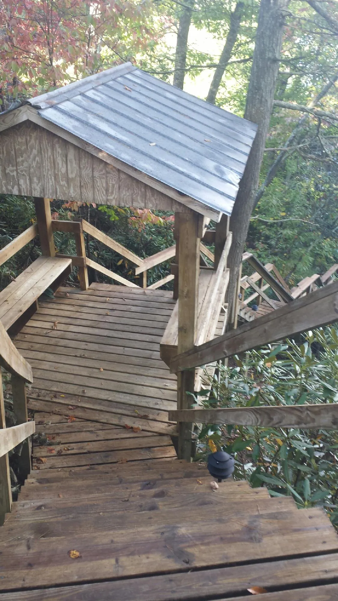 Metal roofed shelter over wooden steps on a wooded walkway — Skylight Repair & Installation work by our crew in Corinne