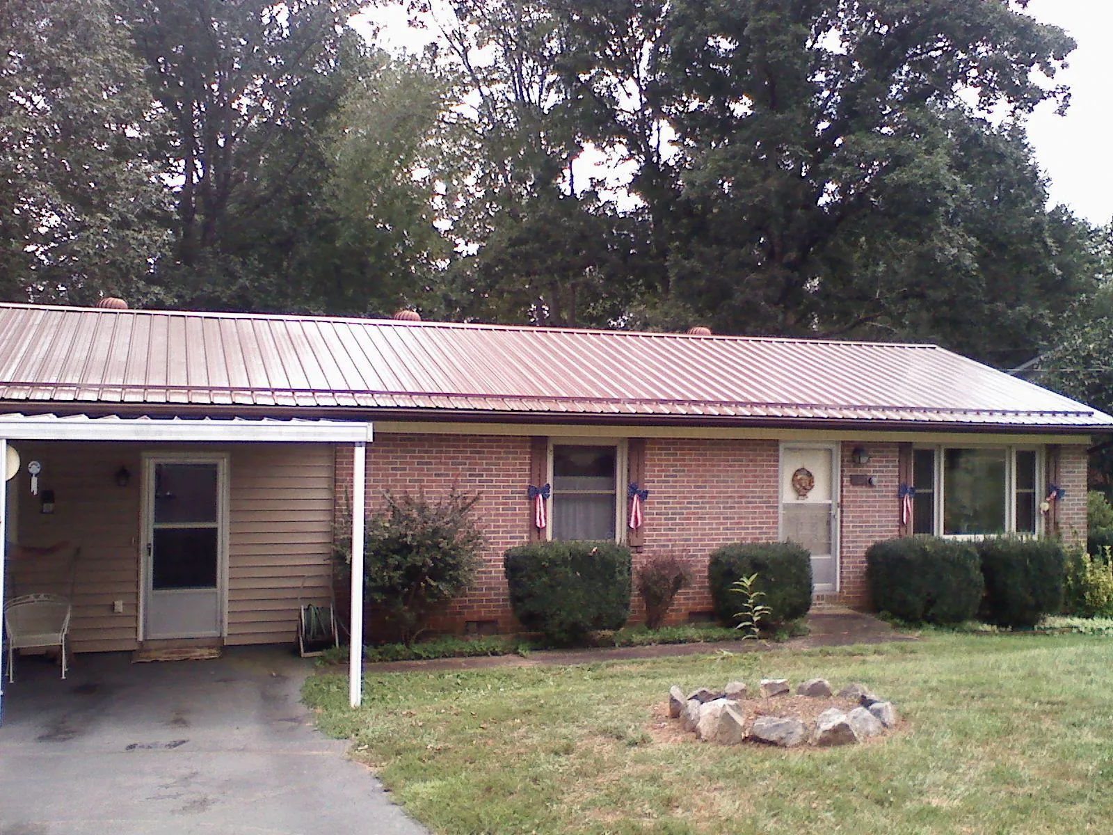 Bronze metal roof and carport on a brick ranch home — Roof Repair work by our crew in Corinne