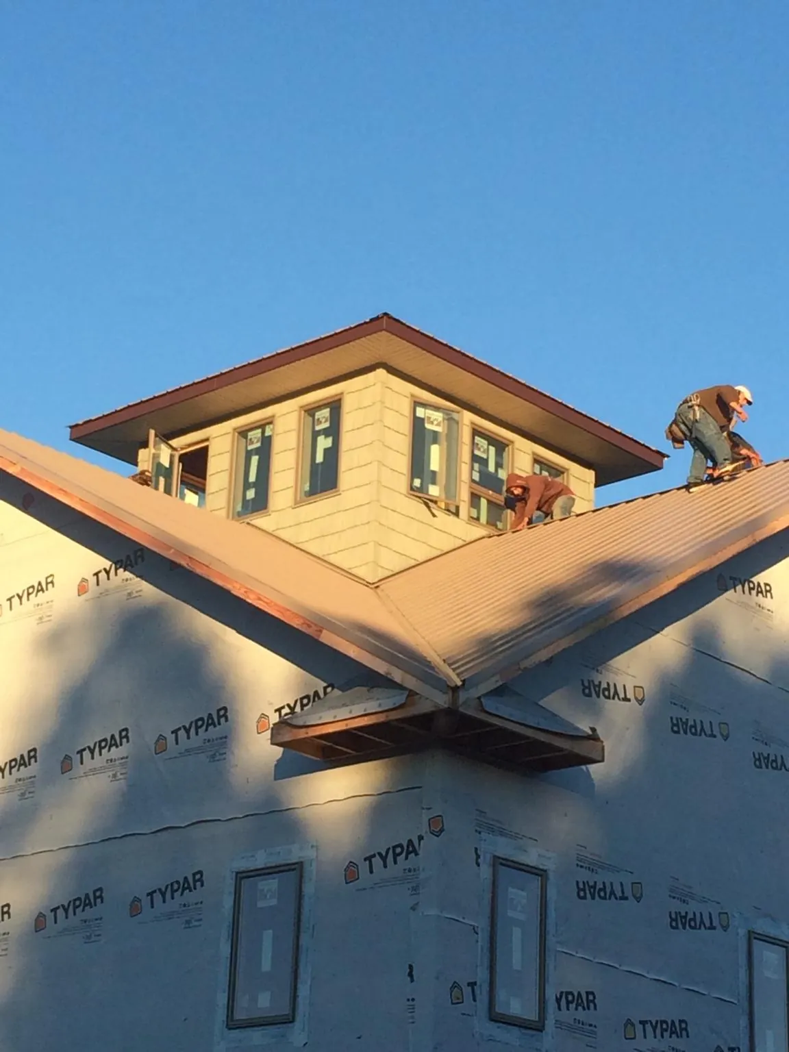 Roofers working around a rooftop cupola on a new metal roof at sunset — Roof Waterproofing in Corinne by Roofing Brothers